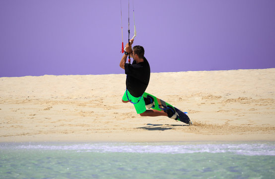 Kite sportsman jumping with splash of water, crystal sea, kiteboarding water sports, active life style. Kiteboarding and kitesurfing water sports, recreational hobby and fun. Sea, beach and clear sky
