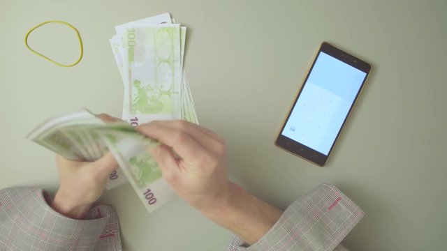 Top view. Male hands count money and summarize the result on the calculator. 