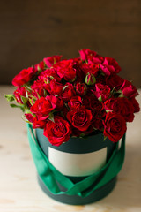 Bouquet of red spray roses in a box on wooden table. copy space. blank for text