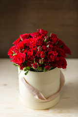 Bouquet of red spray roses in a box on wooden table. copy space. blank for text