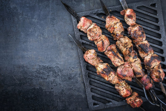 Traditional Russian shashlik on a barbecue skewer as top view on grillage with copy space left