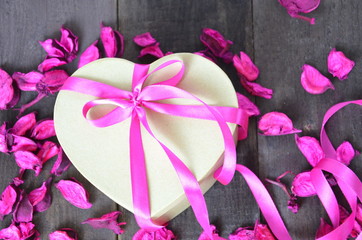 a gift for the day of the holy Valentine. box in the shape of the heart. lilac, raspberry petals red background. texture