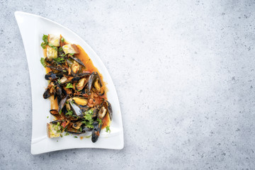 Traditional Italian blue mussel in white wine sauce as close up on a plate with copy space right