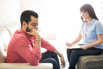 Hispanic man with depression visiting psychologist for solution