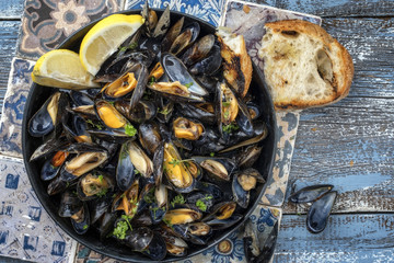 Traditional barbecue Italian blue mussel in white wine as top view in a casserole