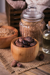 Natural cosmetic oil, sea salt and natural handmade soap with cocoa beans on rustic wooden background