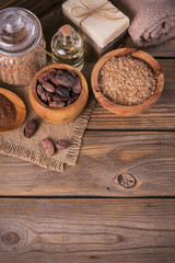 Fototapeta premium Natural cosmetic oil, sea salt and natural handmade soap with cocoa beans on rustic wooden background