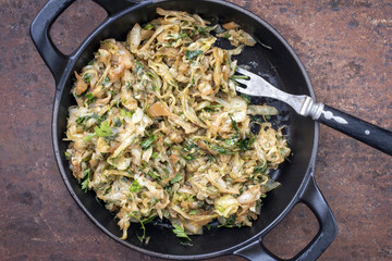 Fresh fried white cabbage as top view in a cast iron pan