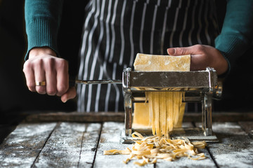 Female preparing homemade tagliatelle with machine on the table,selective focus