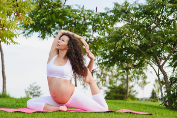 Naklejka na ściany i meble Young pregnant woman doing yoga outdoors