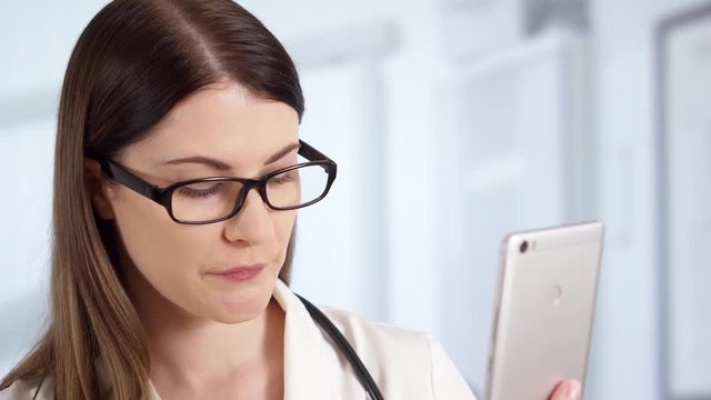 Smiling professional female doctor with stethoscope standing in hospital room talking on phone with patient via messenger app showing bottle of pills. Woman physician at work. Health care concept