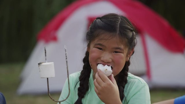 Young girl at summer camp eating a marshmallow