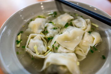 Big Wontons in a bowl with chopsticks on wooden table - Close up