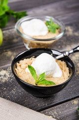 Top view close up Apple crumble dessert with vanilla ice cream, green mint on grey wooden table. fork with cake on tablecloth