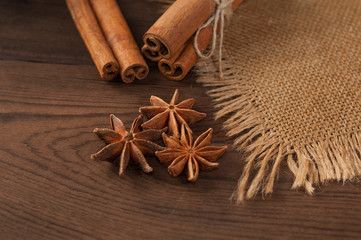 Cinnamon sticks and anise on sackcloth on a wooden background