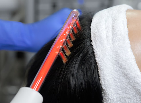 The doctor-cosmetologist makes the procedure Microcurrent therapy On the hair of a beautiful, young woman in a beauty salon.Cosmetology and professional skin care.