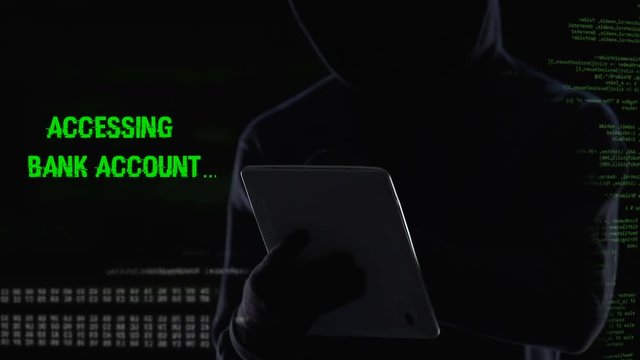 Criminal shutting down bank security system on tablet, illegal funds transfer