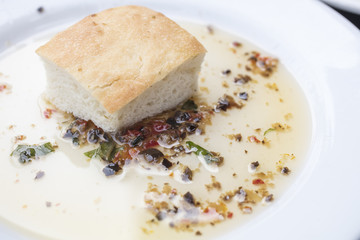 Bread dipping in a seasoned olive oil  on a white plate