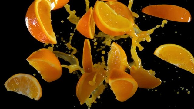 Slices of orange with juise bouncing against to the camera on a black background in slow motion