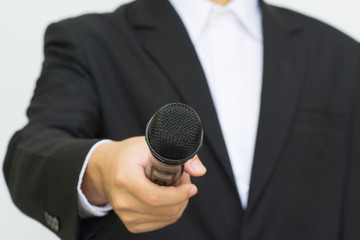 Business man holding a microphone, isolated on grey background