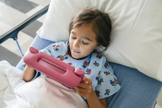 Mixed Race Girl Using Digital Tablet In Hospital Bed