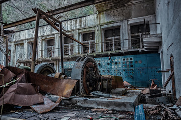 Ruined abandoned hydroelectric power plant. Rusty generator at machinery. Demolished roof. Gagra, Abkhazia