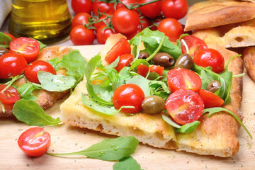 Focaccia with cherry tomatoes, arugula, olives and extra virgin olive oil