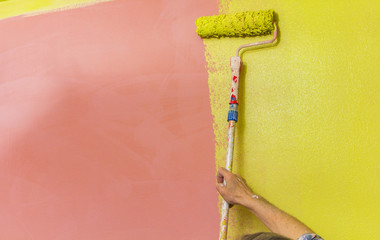 Senior old man painter, painting red wall into lime green, redecorating a room
