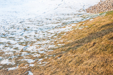 The transition from autumn to winter. Dry yellowed grass half covered with snow