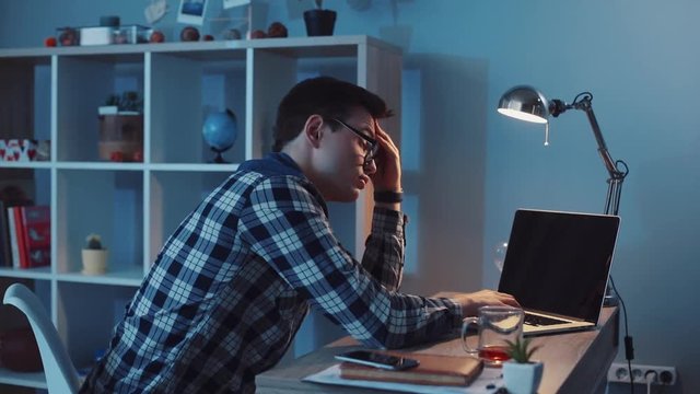 Sleepy businessman working hard on his computer late at night. Web design, programming, modern technologies, making money. Slow motion, camera stabilizer shot, male portrait
