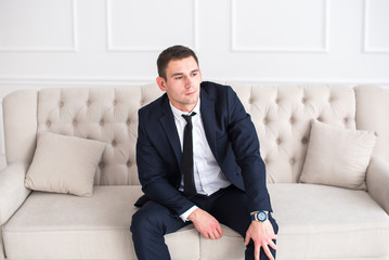 Young serious and confident man in a business suit sitting on the couch