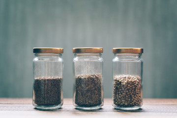 sweet cumin, white cumin and coriander seed in a glass jar on a wooden table