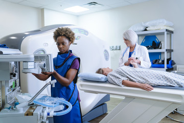 Technician preparing scanner for doctor comforting patient