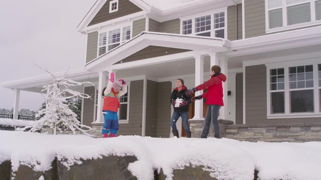 Three kids throwing snow by home in winter