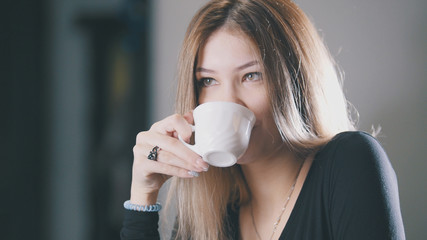 Pretty blonde young woman drinking coffee and smiling in the cafe