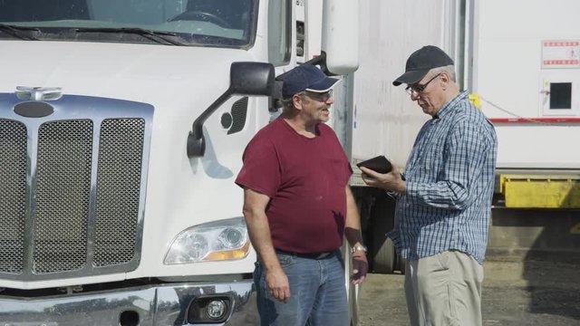 Truck driver and shipping manager look at digital tablet.  Fully released for commercial use.
