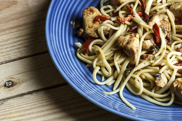 Chinese food on a plate. Chicken with pasta on wooden background.