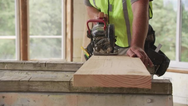 Closeup of construction worker cutting with circular saw