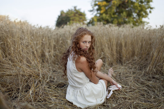 Caucasian girl sitting in wheat
