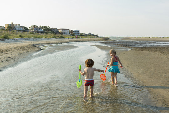 Caucasian brother and sister carrying nets on beach