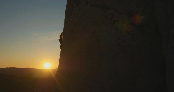 Aerial lift - Man rock climbing outdoors at amazing sunset.
