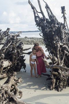 Caucasian mother and daughter examining driftwood on beach