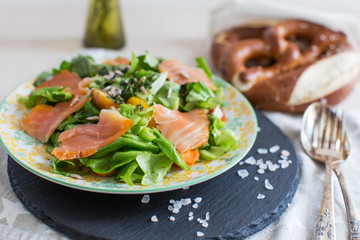 Fresh salad with salmon fish, lettuce and herbs and pretzel 