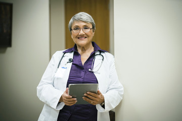 Portrait of smiling mixed race doctor using digital tablet