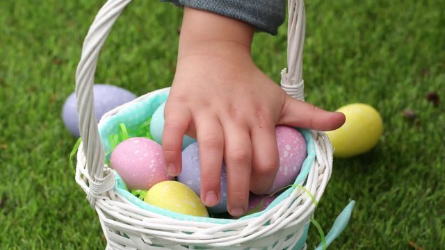 Close-up shot little girl putting Easter eggs into basket