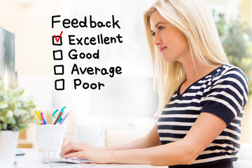 Feedback with happy young woman sitting at her desk in front of the computer