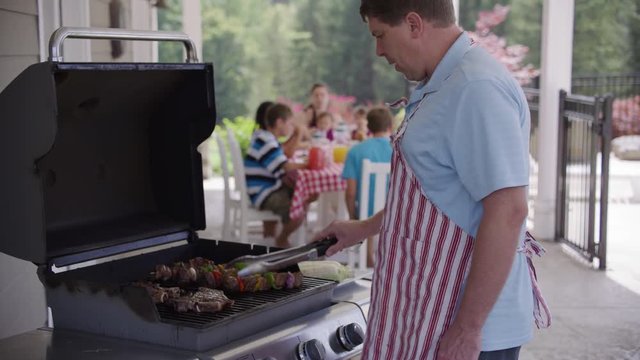 Man cooking with grill at backyard barbeque