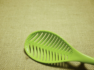 green plastic ladle on sackcloth woven background