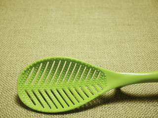 green plastic ladle on sackcloth woven background