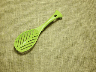 green plastic ladle on sackcloth woven background